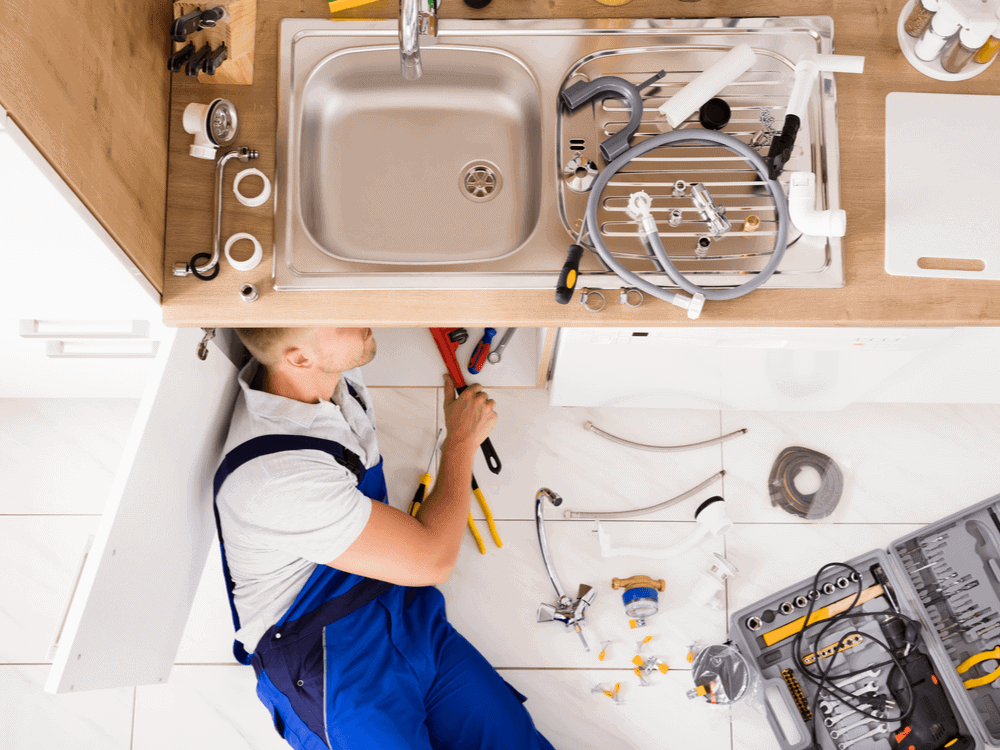 Plumber repairing kitchen sink pipes near Yucca Valley, showcasing plumbing services by HI-DESERT PLUMBING INC